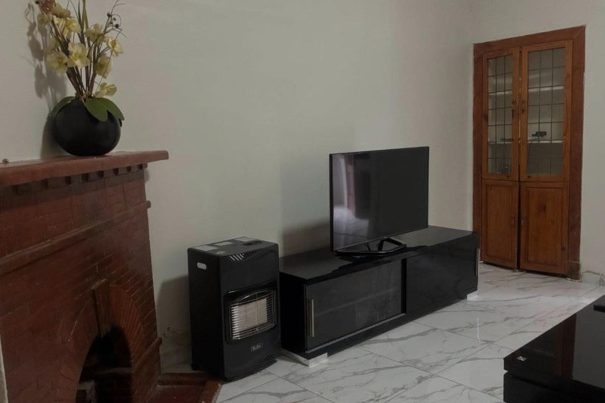 Living room featuring a brick fireplace, tiled flooring, and a built-in wooden cabinet.