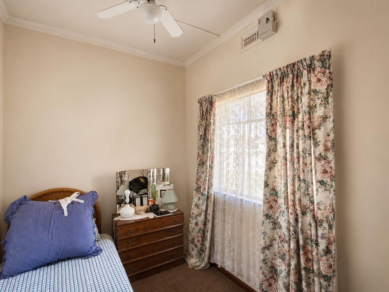 A bedroom featuring neutral walls, carpet flooring, a ceiling fan, and ducted air conditioning.