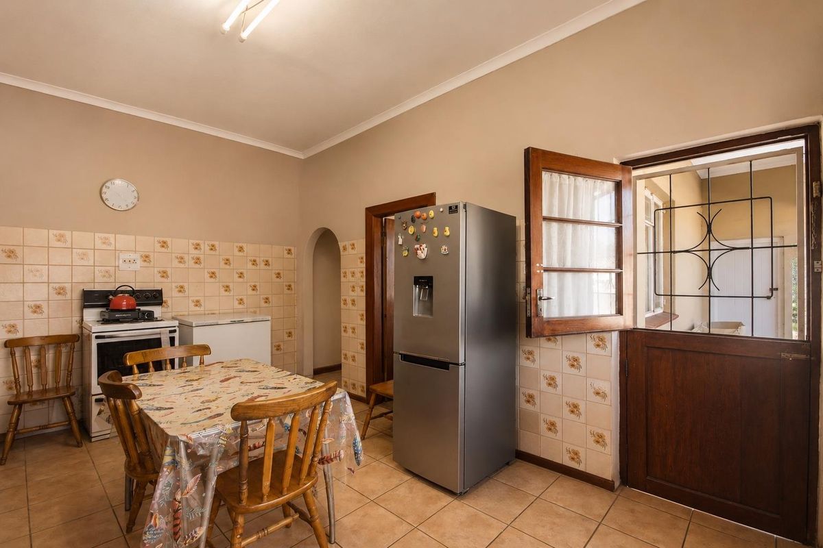 A functional kitchen featuring tiled flooring, a tiled splashback, and direct access to an outdoor area through a timber door with a security gate.