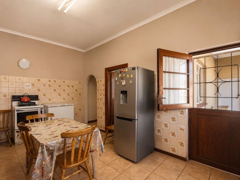 A functional kitchen featuring tiled flooring, a tiled splashback, and direct access to an outdoor area through a timber door with a security gate.