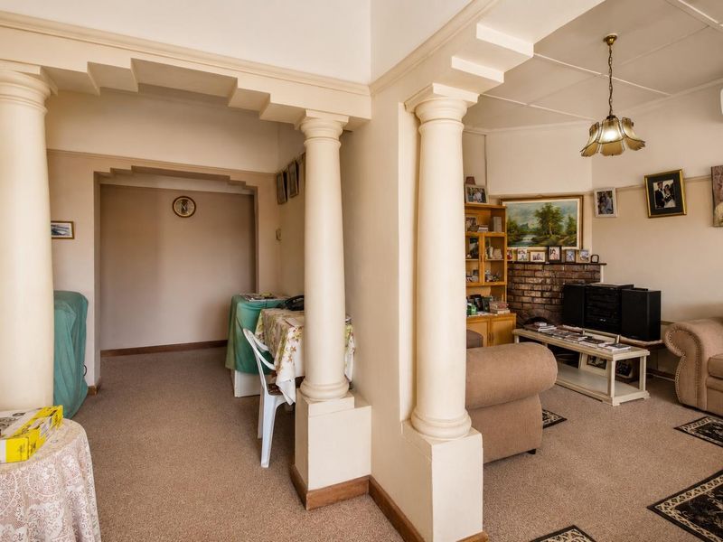 A living room featuring decorative columns, a brick fireplace, and a split-system air conditioner, offering a traditional layout with connected living and dining spaces.