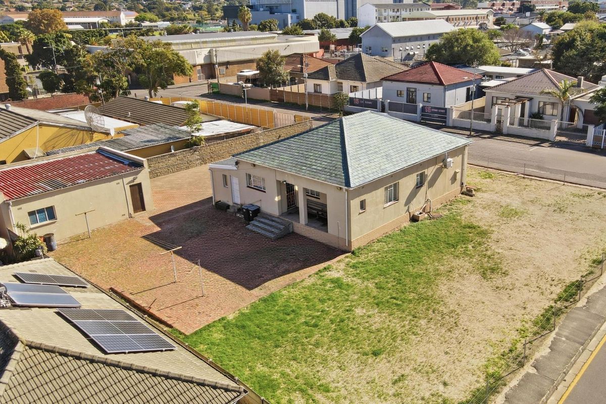 Aerial view of the property showing the main house, detached garage, paved courtyard area, and solar water heating installation on the roof.