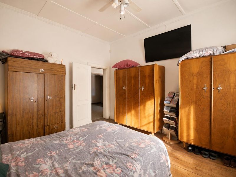 A bedroom featuring hardwood flooring, a ceiling fan, and a neutral color palette, offering a functional space with classic architectural details.