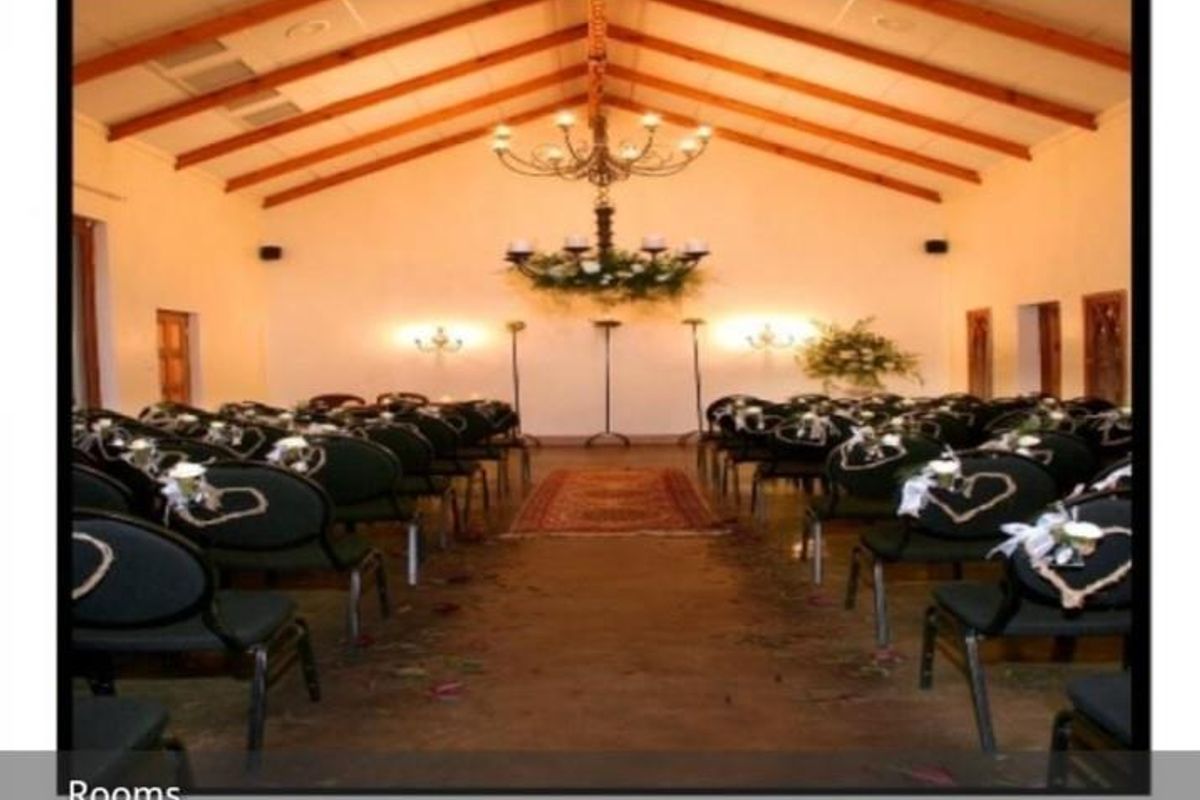 A spacious hall featuring exposed timber roof trusses, a vaulted ceiling, and a central chandelier, currently set up as an event or ceremony space.