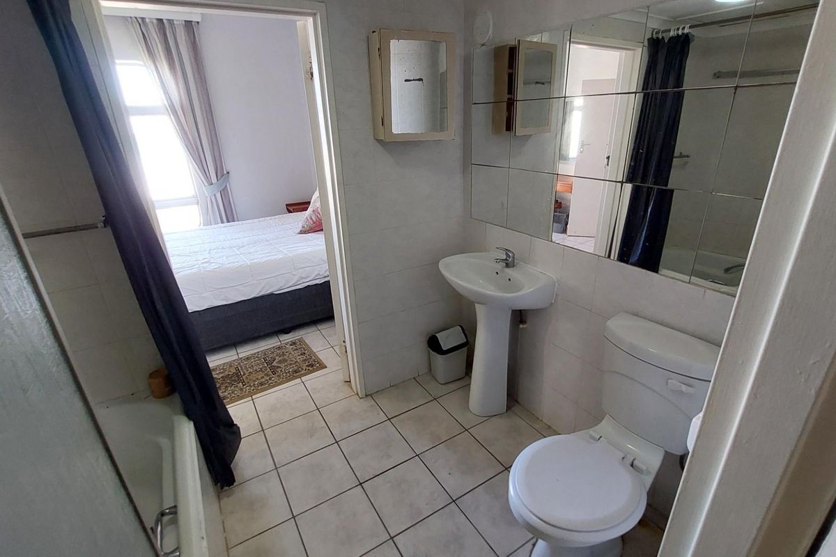 A functional bathroom featuring a pedestal basin, toilet, and bathtub, with direct access to the adjacent bedroom.