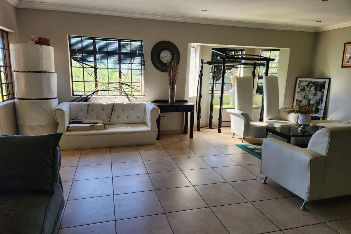 Spacious living room featuring large windows, tiled flooring, and recessed ceiling lighting, offering a versatile area for relaxation and family gatherings.