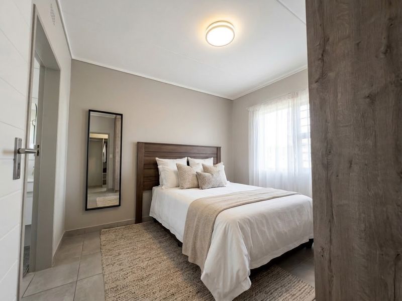 A well-maintained bedroom featuring neutral wall tones, tiled flooring, and a flush mount ceiling light, offering a clean and comfortable living space.