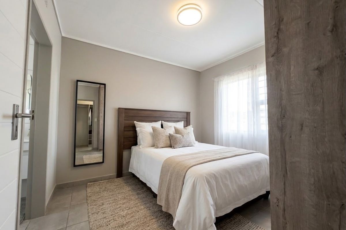 A well-maintained bedroom featuring neutral wall tones, tiled flooring, and a flush mount ceiling light, offering a clean and comfortable living space.