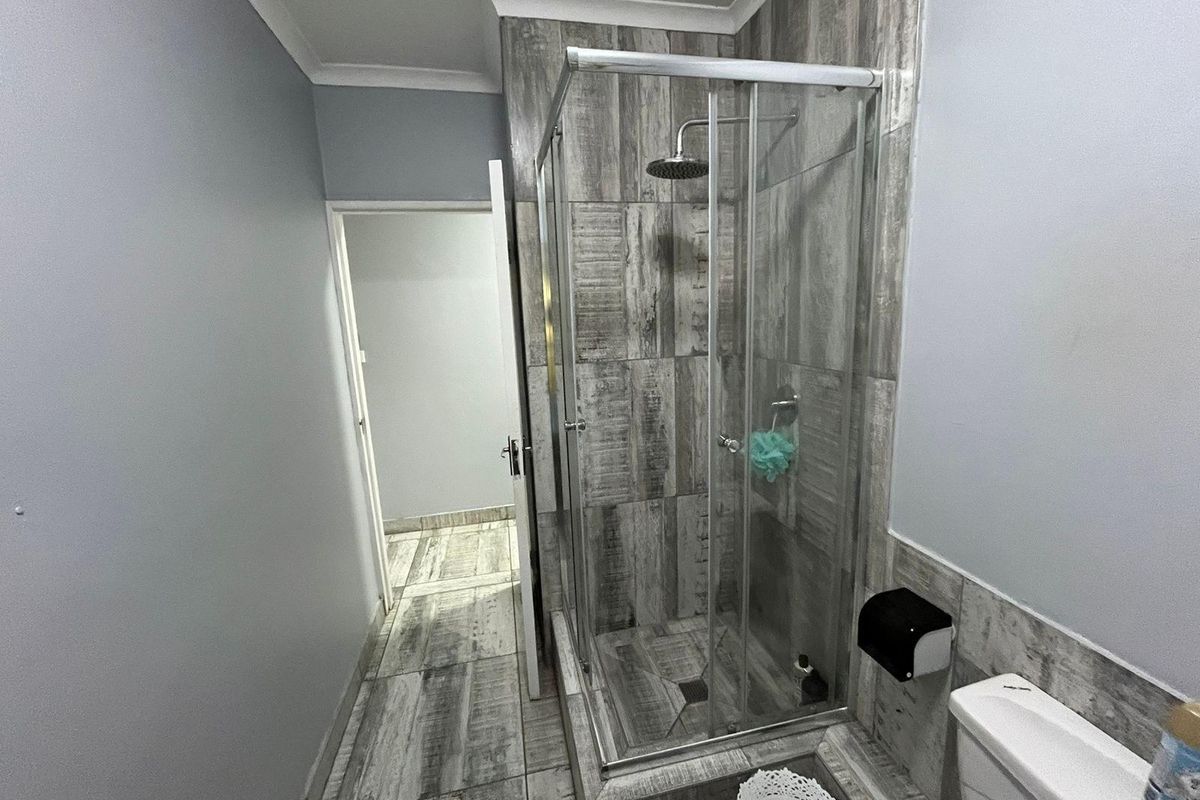 Modern bathroom featuring a glass-enclosed shower with a rain shower head and contemporary wood-look ceramic tiling throughout.