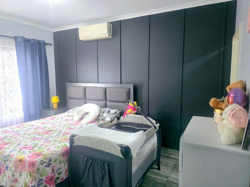 A bedroom featuring a dark accent wall, tiled flooring, and a wall-mounted split-system air conditioning unit.