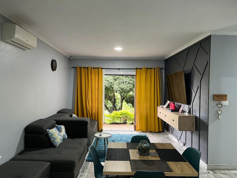 Open-plan living area featuring a modern feature wall, floating media console, split-system air conditioning, and direct access to the outdoor garden space.