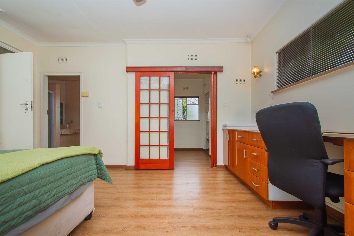 A bedroom featuring wood-look laminate flooring, built-in cabinetry, and a sliding wooden door leading to an adjacent room.