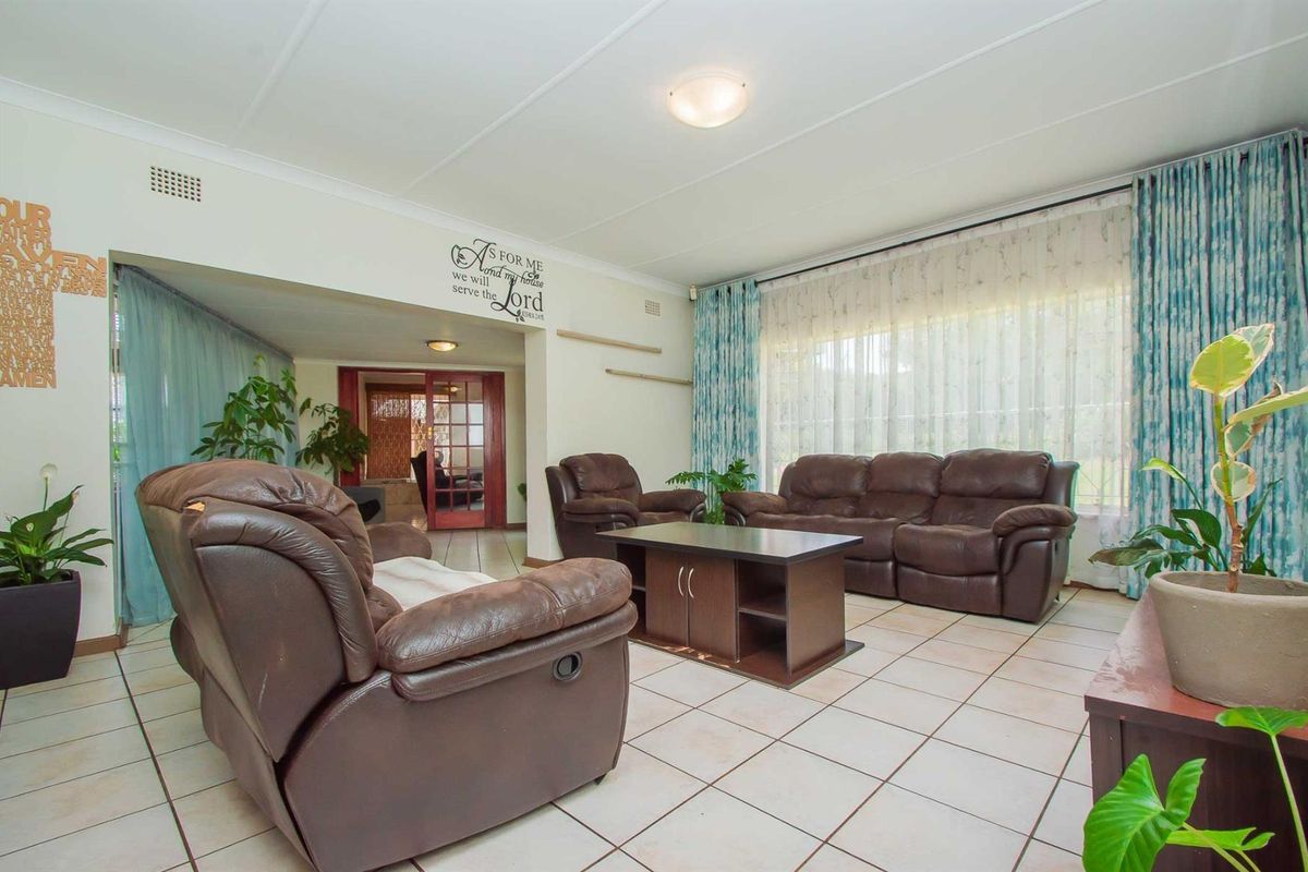 Spacious living room featuring tiled flooring, large windows with curtains, and an open-plan layout leading to an adjacent room.