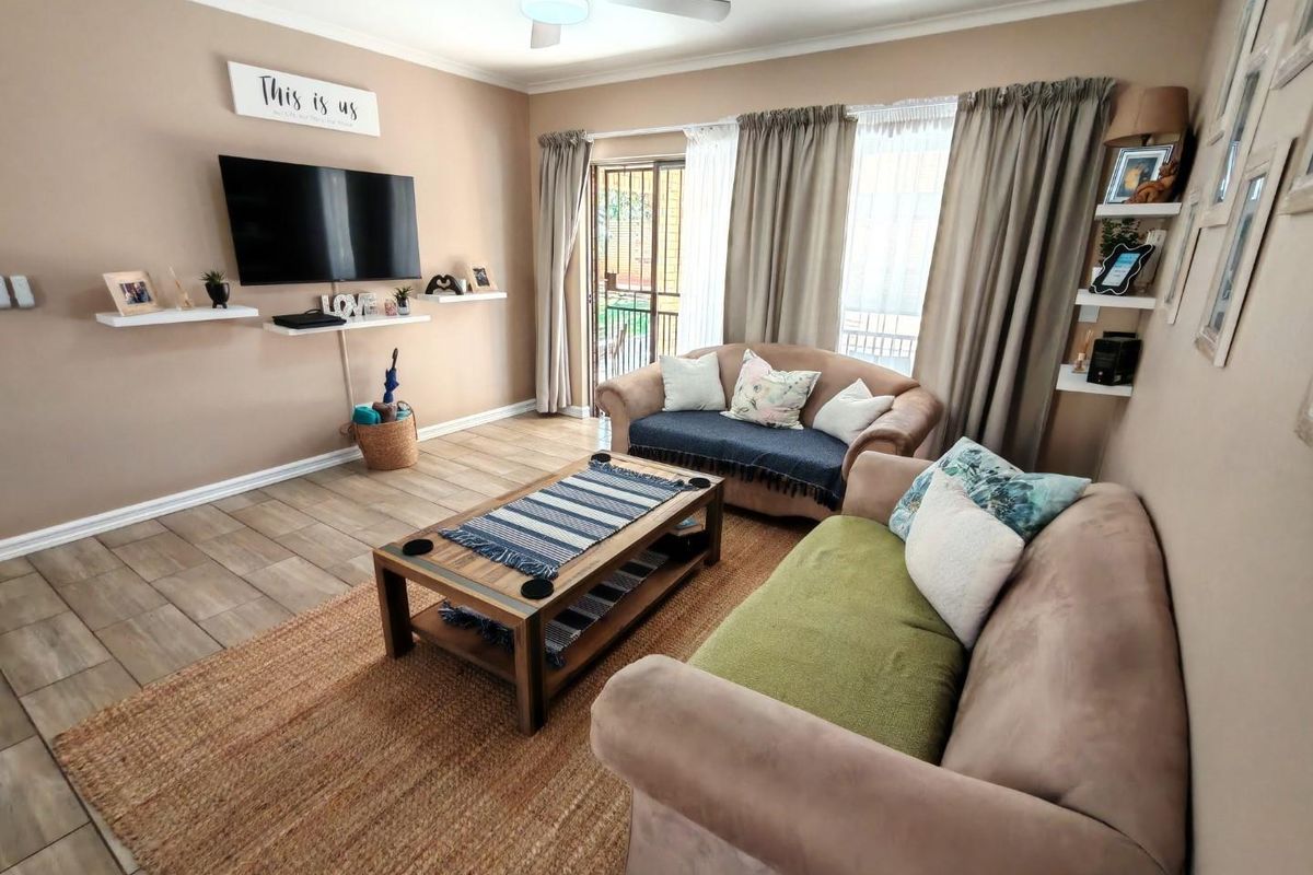 A comfortable living room featuring tiled flooring, a ceiling fan, and sliding glass doors providing access to an outdoor patio area.