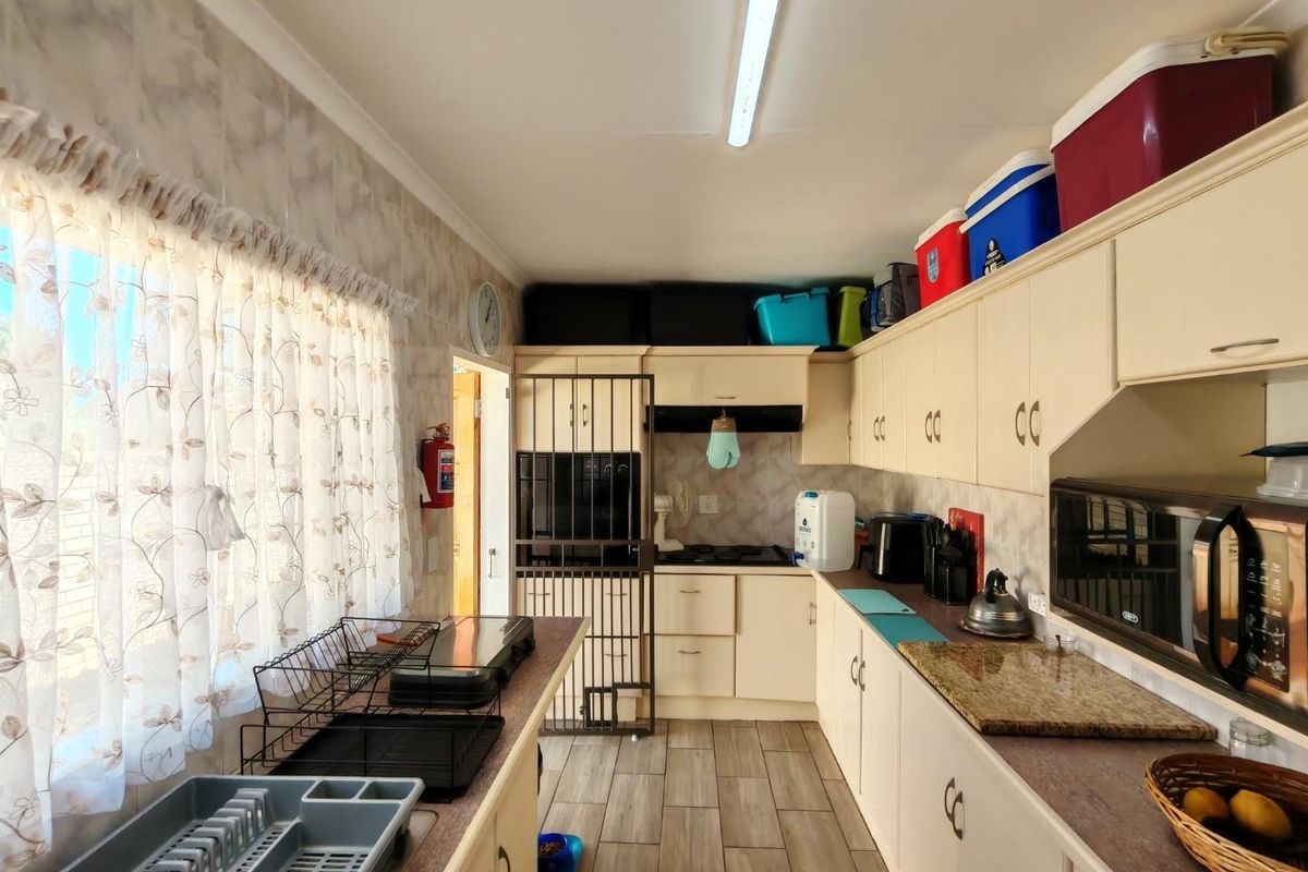 A functional kitchen featuring laminate cabinetry, stone-look countertops, tiled flooring, and a built-in hob with an extractor fan.