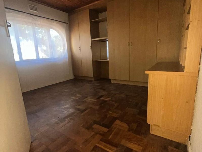 A bedroom featuring classic parquet flooring, a timber-paneled ceiling, and extensive built-in wooden cabinetry providing ample storage space.