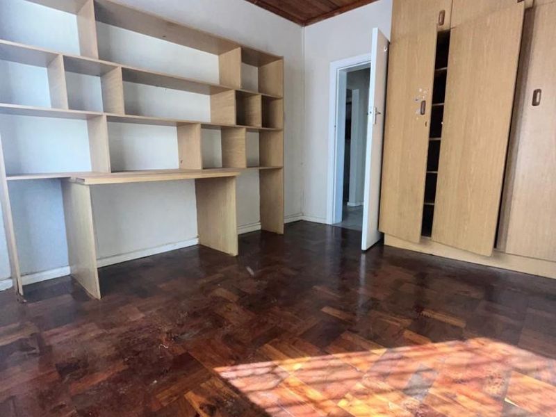 Bedroom featuring parquet flooring, a timber-paneled ceiling, built-in wooden cupboards, and a custom-fitted desk unit with integrated shelving.