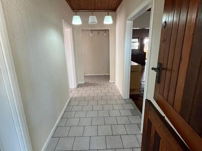 A tiled hallway featuring a timber-clad ceiling and pendant lighting, providing access to multiple rooms within the home.