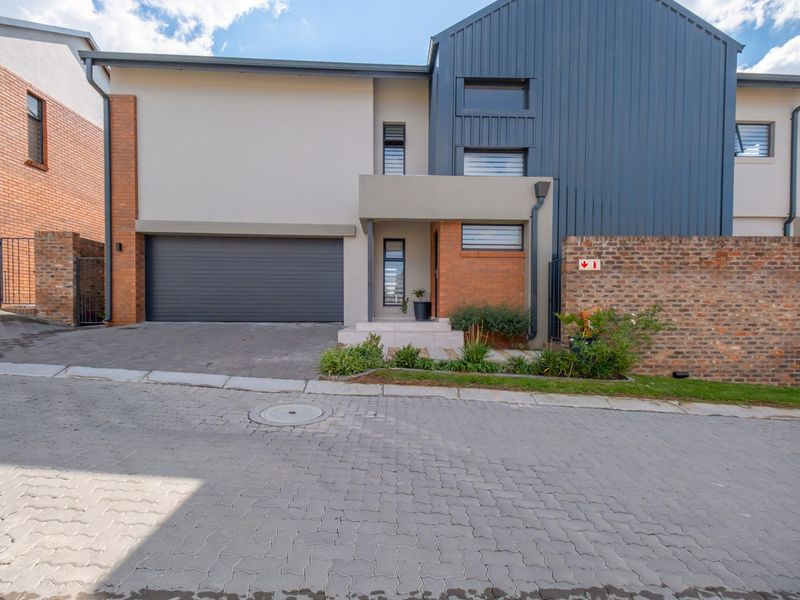 Modern double-story residential facade featuring a combination of brickwork, smooth plaster, and metal cladding with an integrated single garage and paved driveway.