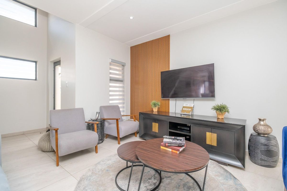 Modern living room featuring high ceilings, large windows, and a stylish timber slat feature wall.