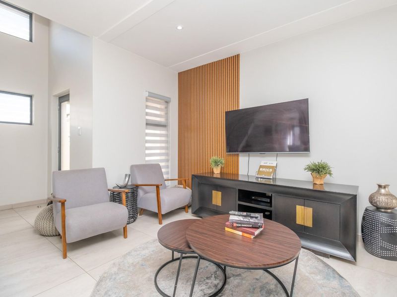 Modern living room featuring high ceilings, large windows, and a stylish timber slat feature wall.