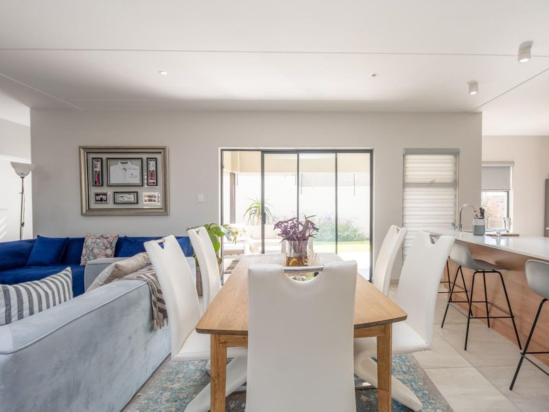 Open-plan living and dining area featuring tiled flooring, recessed lighting, and sliding glass doors leading to an outdoor patio space.