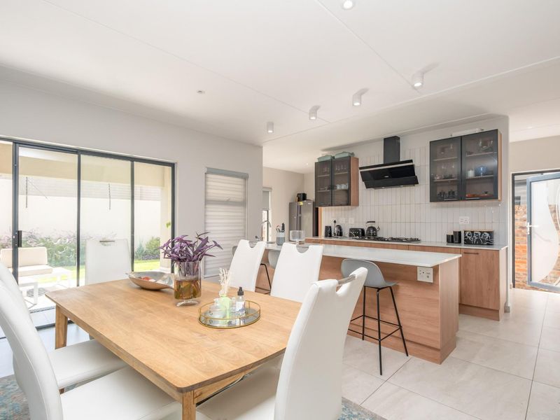 Open-plan kitchen and dining area featuring modern cabinetry, a central island with breakfast bar, and sliding glass doors leading to the patio.