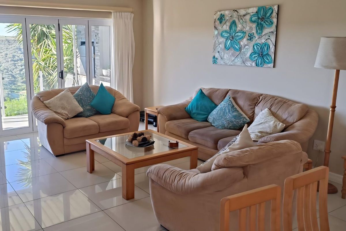 A bright and spacious living room featuring large glass sliding doors that open to an outdoor area, complemented by polished floor tiles.