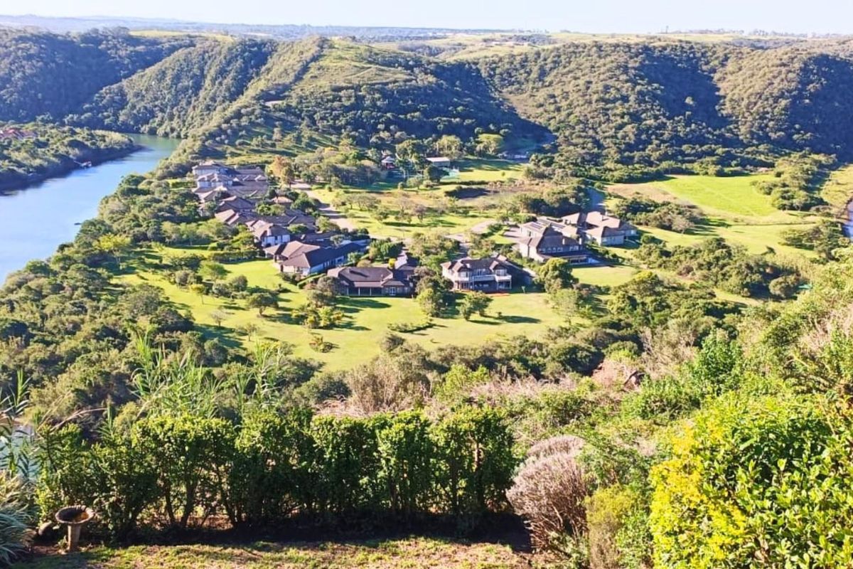 Elevated aerial view of the residential estate, showcasing the surrounding natural landscape, river, and lush green grounds.