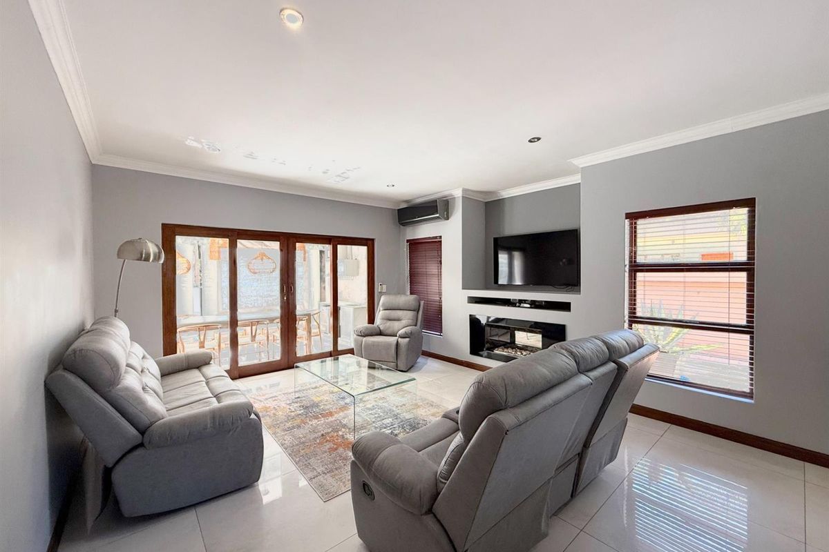 Spacious living room featuring tiled flooring, a built-in fireplace, air conditioning unit, and large sliding doors providing access to the outdoor patio area.