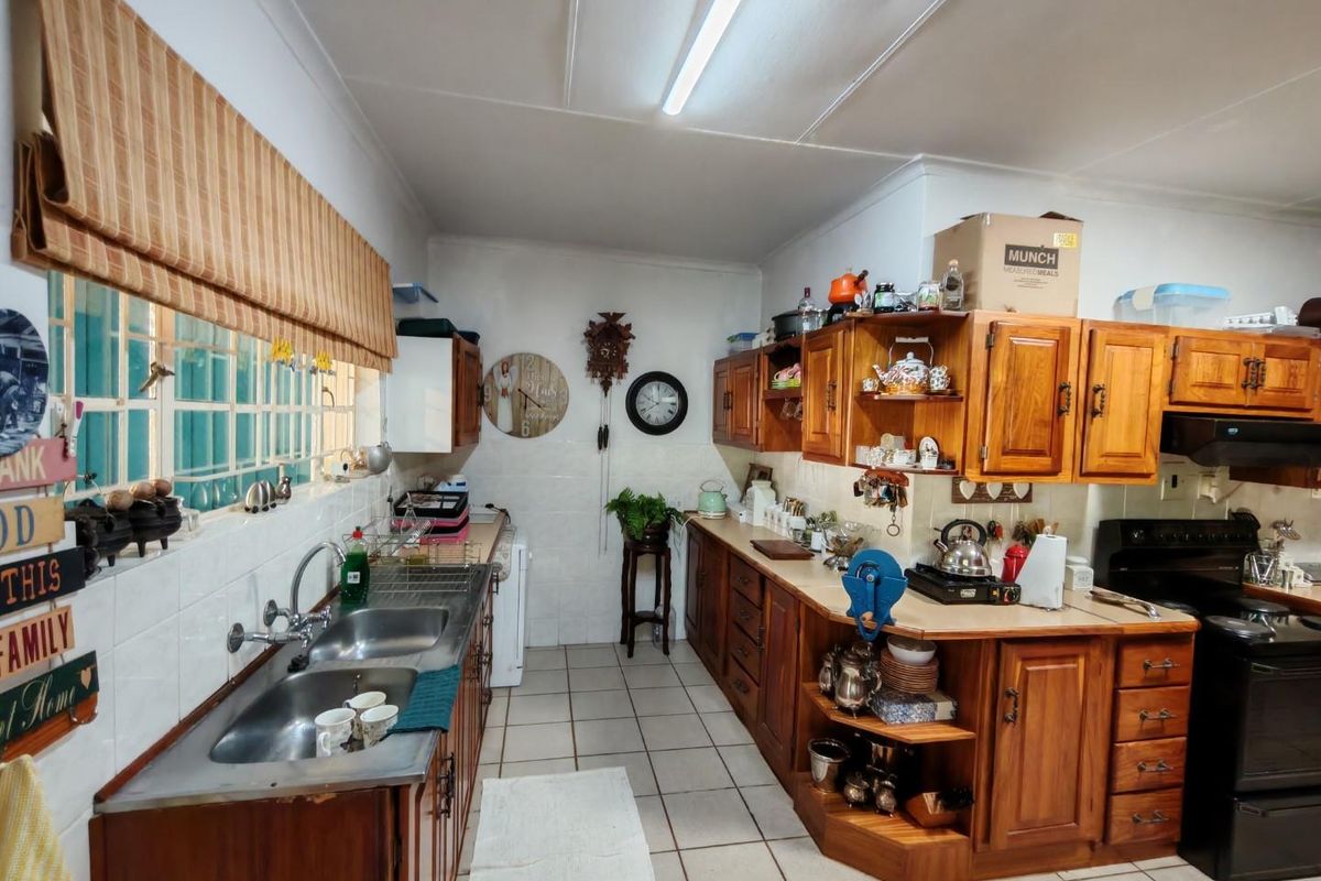 A functional kitchen featuring traditional wooden cabinetry, double stainless steel sink, tiled flooring, and integrated stove area.