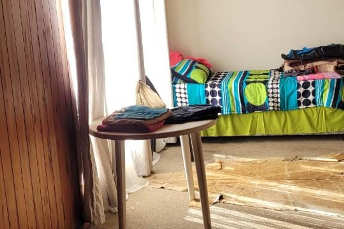 A bedroom featuring dated wood-paneled walls and ceiling, carpeted flooring, and large windows allowing natural light.