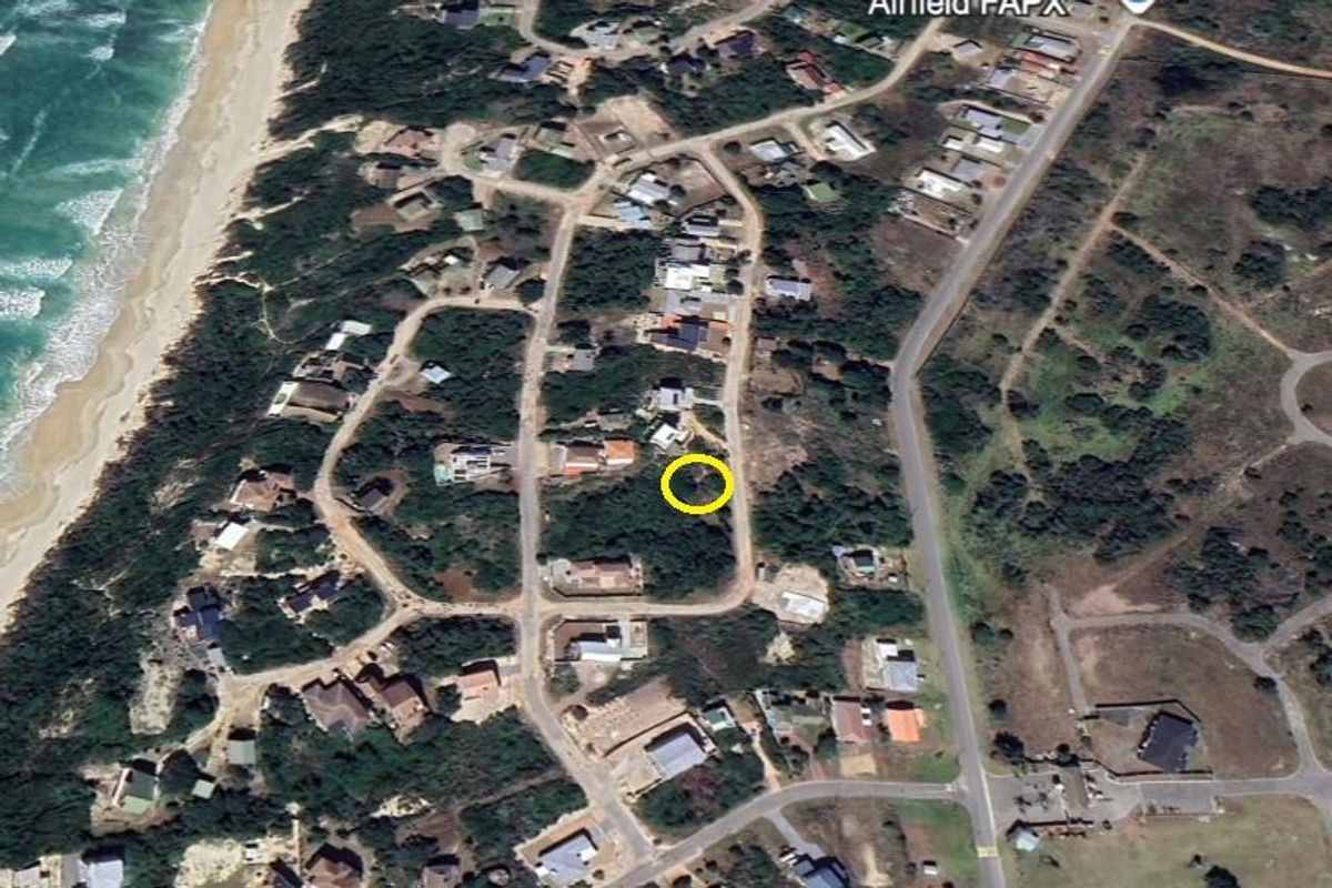 Aerial view of a vacant residential plot in a coastal estate, highlighting the property location within the surrounding neighborhood and proximity to the beach.
