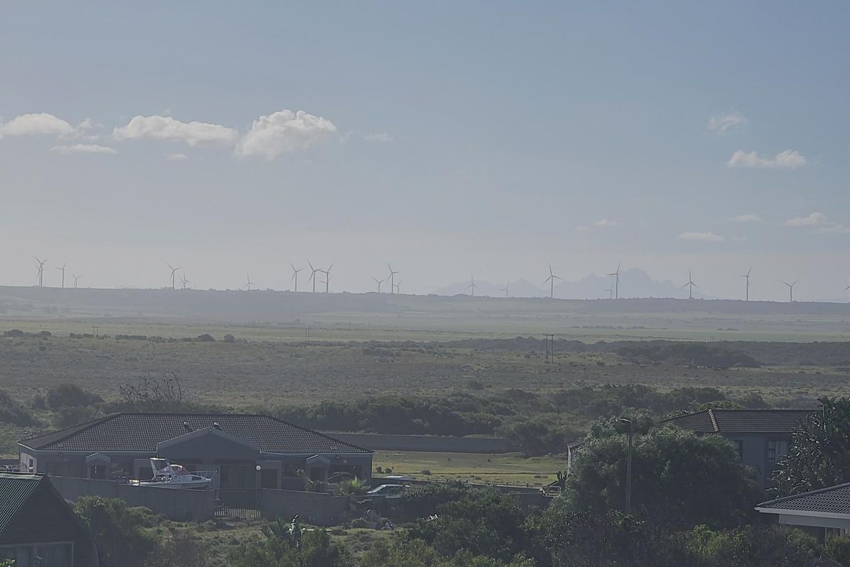 A scenic landscape view featuring open fields and distant wind turbines under a clear sky.