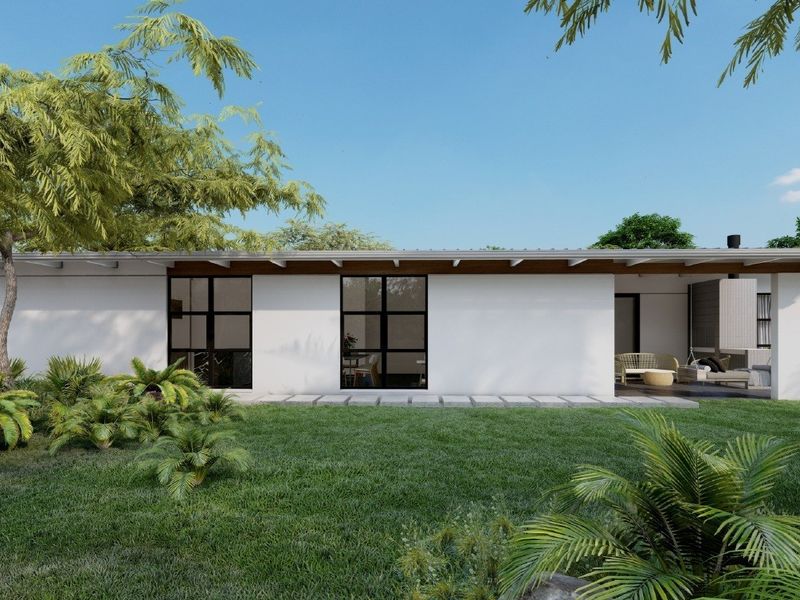 A modern rear exterior view featuring a clean white facade, black-framed windows, exposed timber rafters, and a covered patio overlooking a landscaped garden.