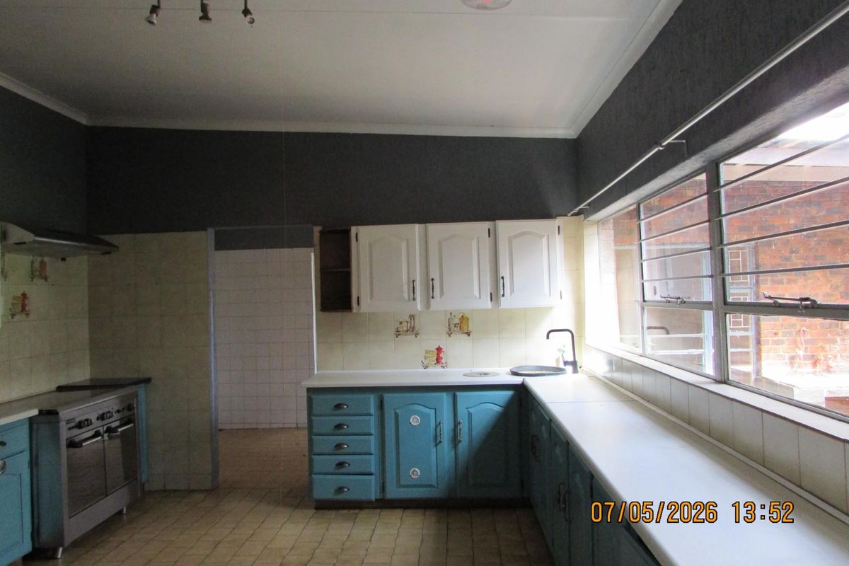 A functional kitchen featuring built-in cabinetry, a stainless steel stove with extractor fan, and tiled surfaces, offering a practical layout for daily use.