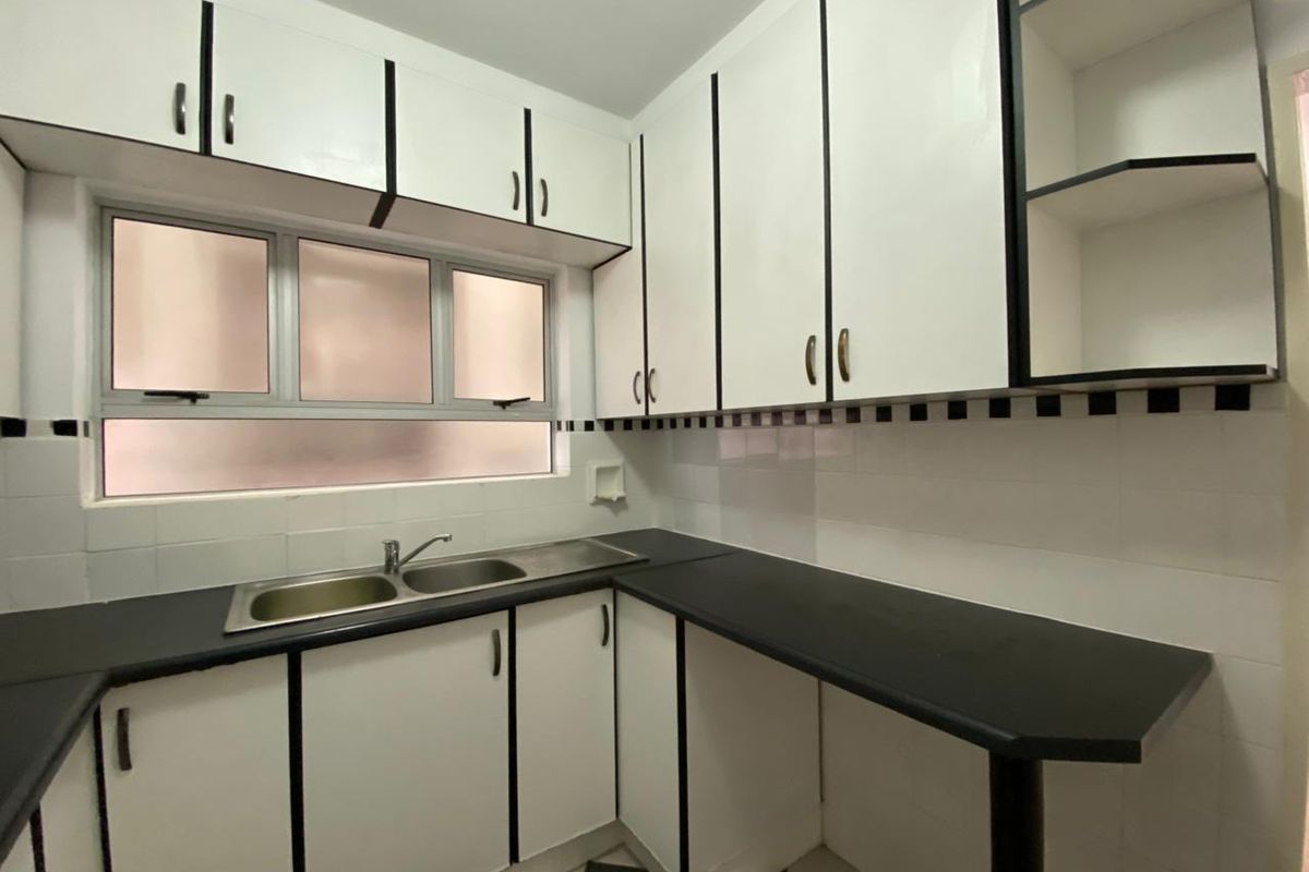 A functional kitchen featuring white cabinetry with black trim, dark laminate countertops, a double stainless steel sink, and a tiled backsplash.