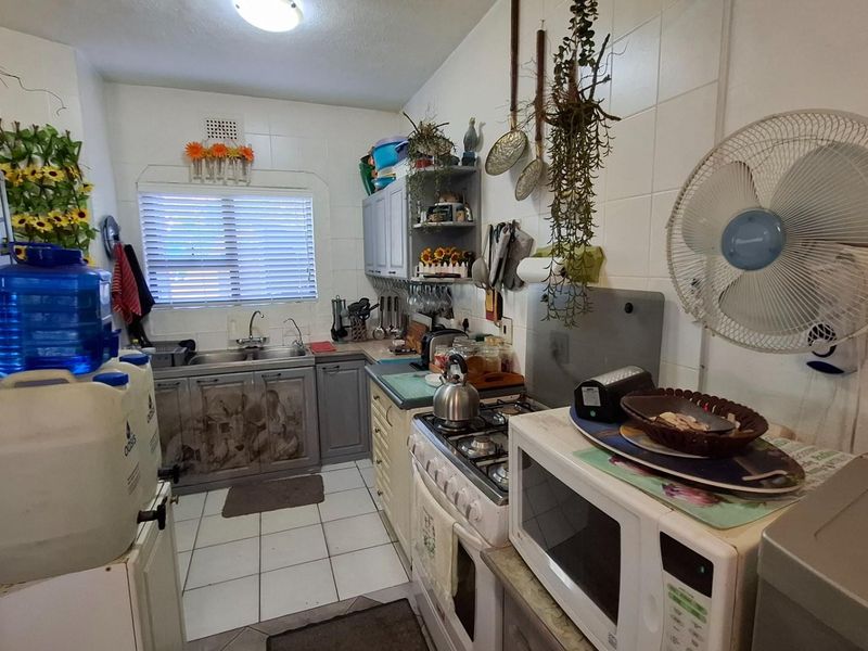 Compact kitchen featuring built-in cabinetry, a gas hob, oven, and tiled finishes. The space offers functional layout potential for a modern renovation.