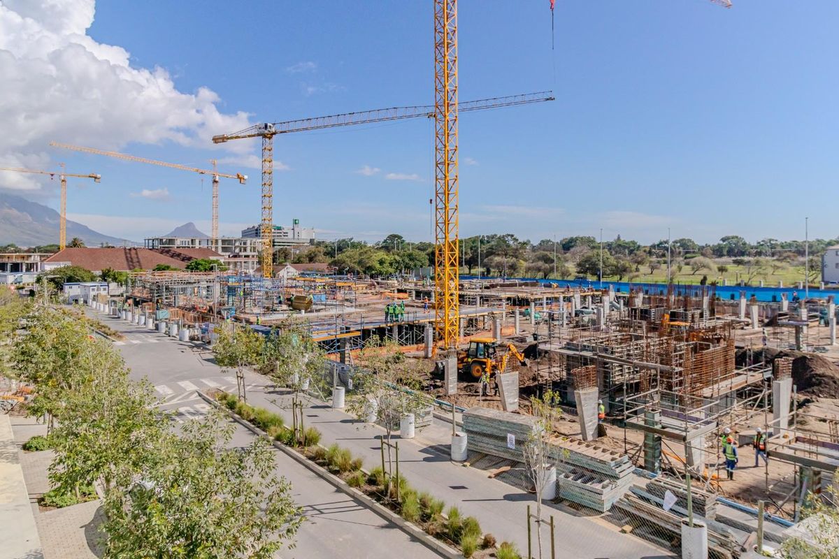 An elevated view of an active construction site featuring multiple tower cranes and ongoing structural development of a new building project.