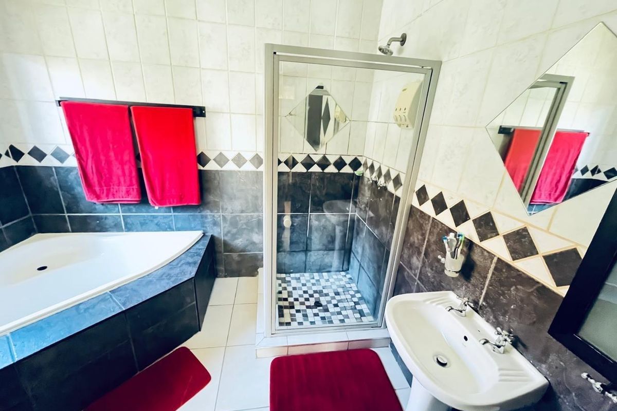 A functional bathroom featuring a corner bathtub, a separate glass-enclosed shower, and a pedestal basin with tiled wall finishes.