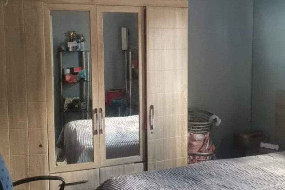 A bedroom featuring a built-in wooden wardrobe with mirrored panels and neutral wall finishes.