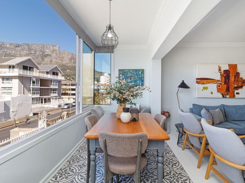Bright open-plan living and dining area featuring large windows with mountain views, decorative floor tiling, and modern ceiling finishes.