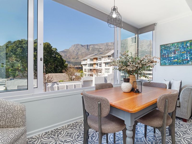 Enclosed balcony or sunroom featuring large windows with mountain views, patterned floor tiles, and a modern pendant light fixture.