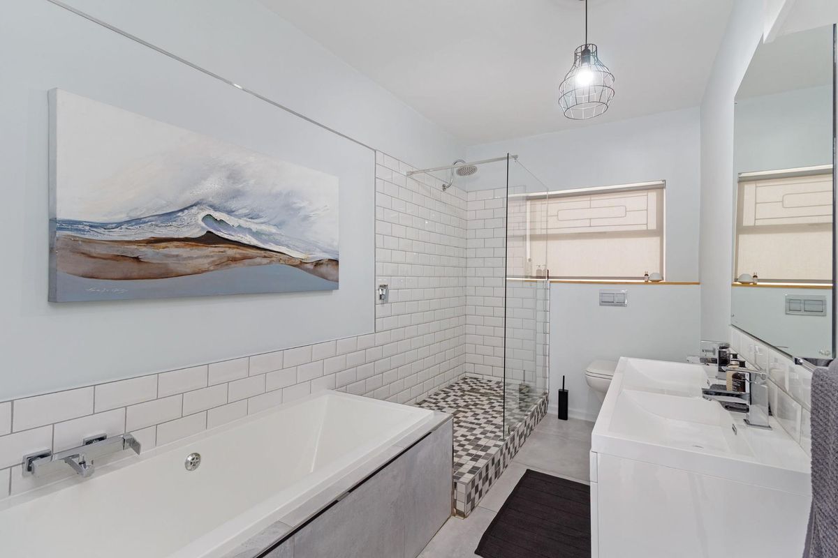 Modern bathroom featuring a walk-in shower with mosaic tiling, a built-in bathtub, and a sleek double vanity with contemporary chrome fixtures.