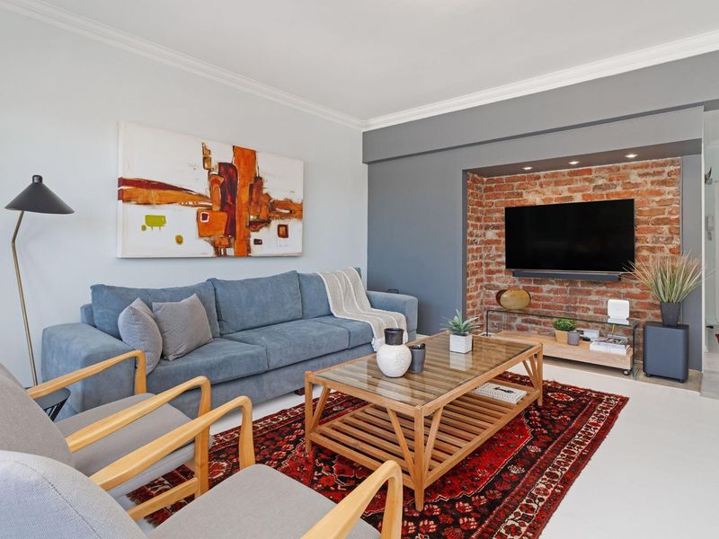 A well-maintained living room featuring a striking exposed brick feature wall with a recessed alcove and integrated downlighting.