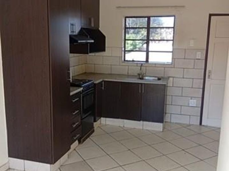 A functional kitchen featuring dark wood cabinetry, tiled backsplash, and tiled flooring, offering a clean and practical space for culinary activities.