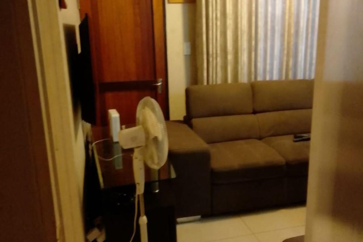 A view into a living room featuring tiled flooring and a wooden door, providing a functional and comfortable living space.