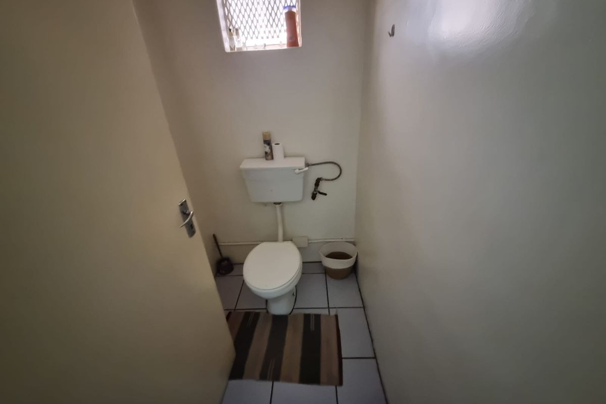 A compact, functional restroom featuring a standard toilet, tiled flooring, and a small high-level window for ventilation.