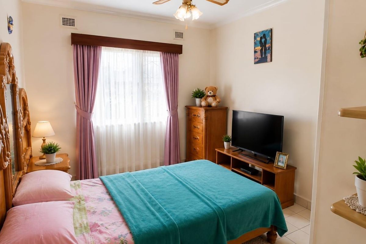 A well-maintained bedroom featuring tiled flooring, a ceiling fan, and a window with fitted curtain rails.