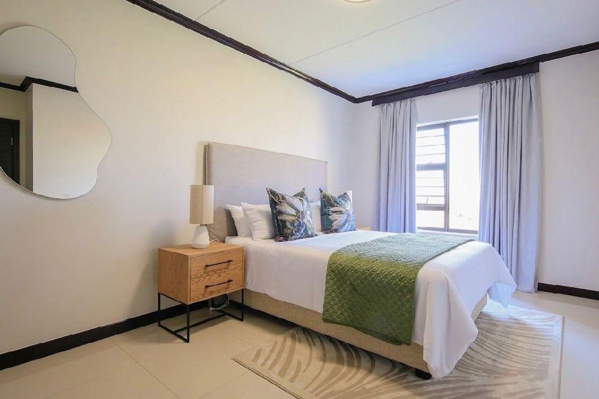 A well-maintained bedroom featuring tiled flooring, dark crown molding, and a large window with curtain tracks.